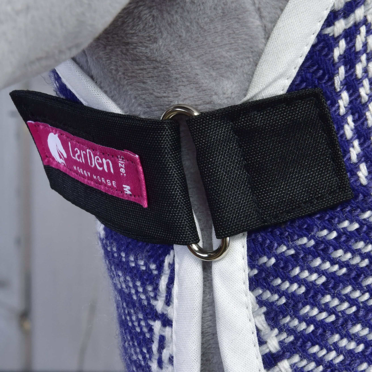 Chest closure of the Set Harmony Victory blanket: black strap, metal ring, pink LarDen label and white binding