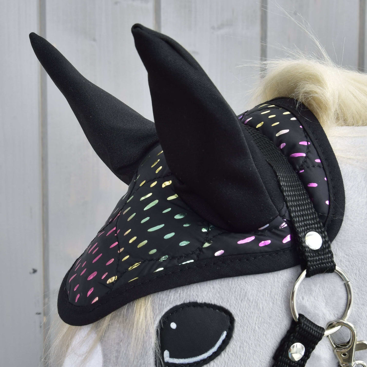 Close-up van het oornetje uit de Set Dreamy met hoge zwarte oren en glinsterende regenboogstippen boven een zwart halster