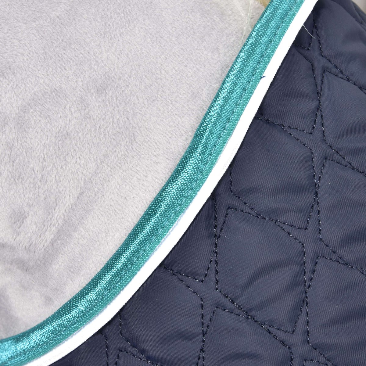 Close-up of the Set Supreme Turquoise blanket edge: navy quilting, white piping and shiny turquoise binding