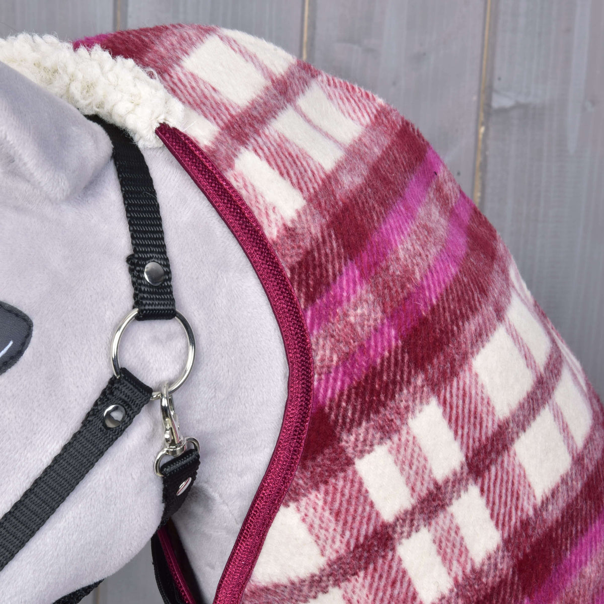 Gros plan sur la bordure bordeaux et le tissu à carreaux rose et crème le long de l’encolure d’un Hobby Horse gris