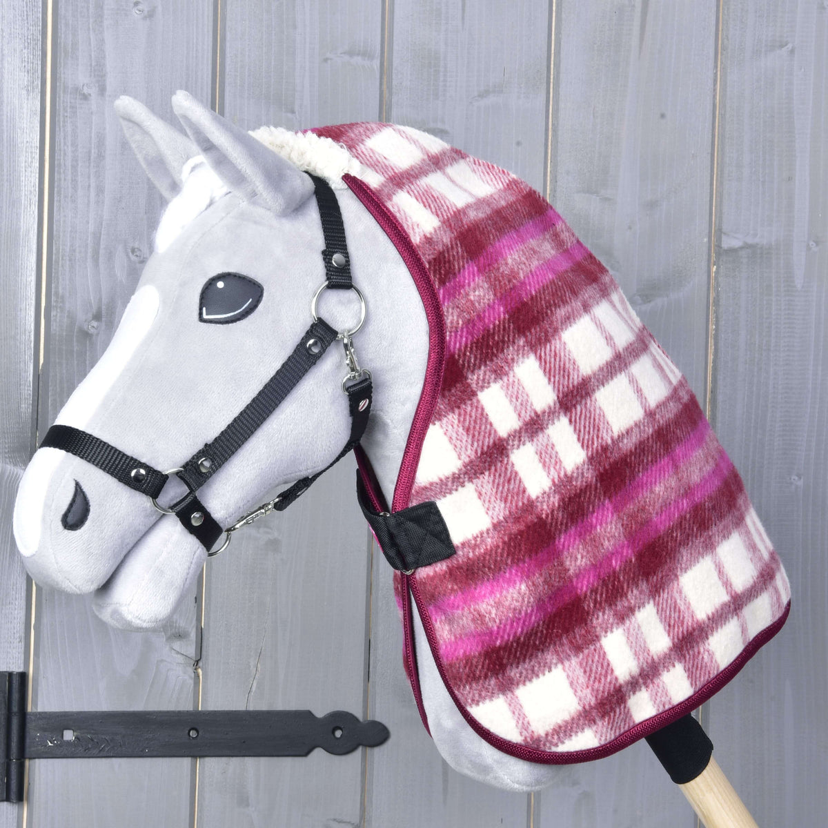 Hobby Horse gris avec licol noir portant la couverture d’écurie à carreaux bordeaux et roses avec sangle avant noire
