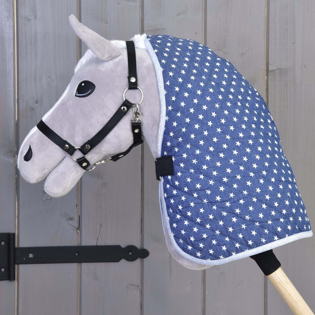 Hobby Horse gris de profil dans la couverture d’écurie Star, étoiles blanches sur matelassage marine jusqu’au bâton