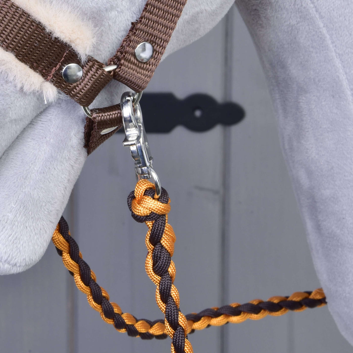 Cordes tressées orange et marron suspendues au mousqueton sous le menton d’un Hobby Horse gris au licol marron