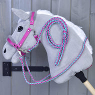 Lichtgrijze Hobby Horse in het roze halster met bont, met gevlochten roze-turquoise teugels en een opgerold halstertouw