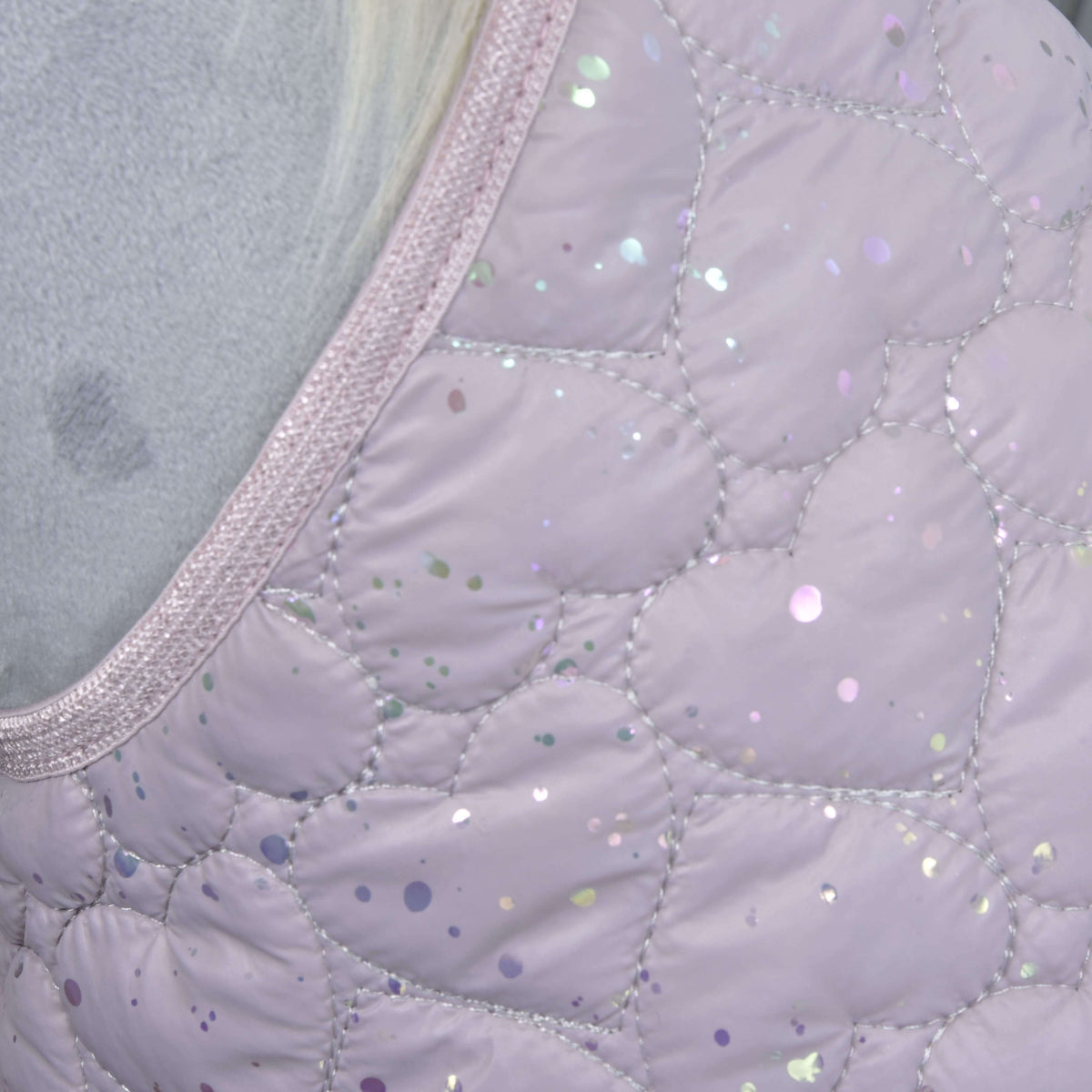 Detail van de lila dekenstof met hartvormig stiksel, iriserende glitterstipjes en een glinsterende bies