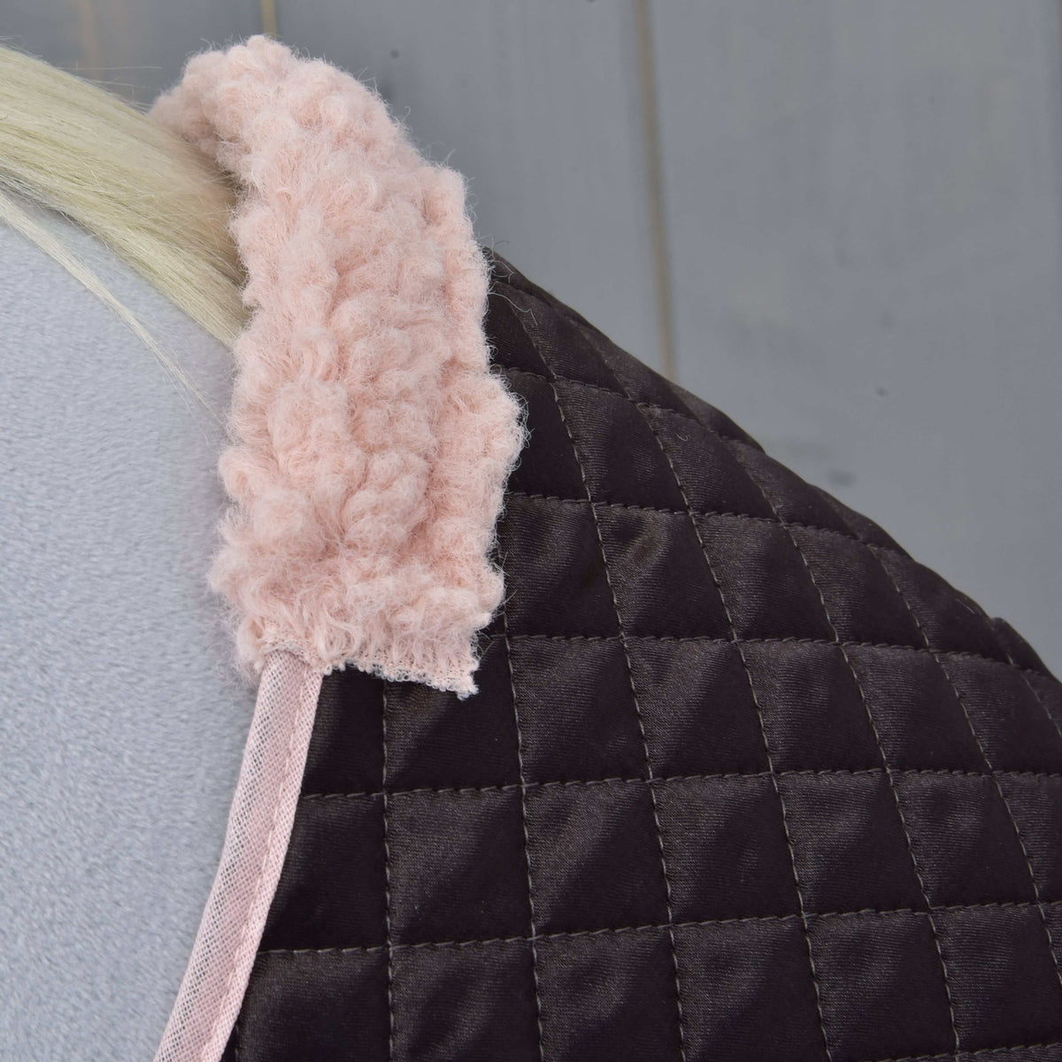 Gros plan sur le col teddy rose tout doux et la bordure rose de la couverture matelassée brun foncé de l’ensemble Thermo Sweety