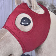 Close-up van het bordeauxrode masker zonder oren op een beige Hobby Horse, met gestikte ronde oogopening en oorgat
