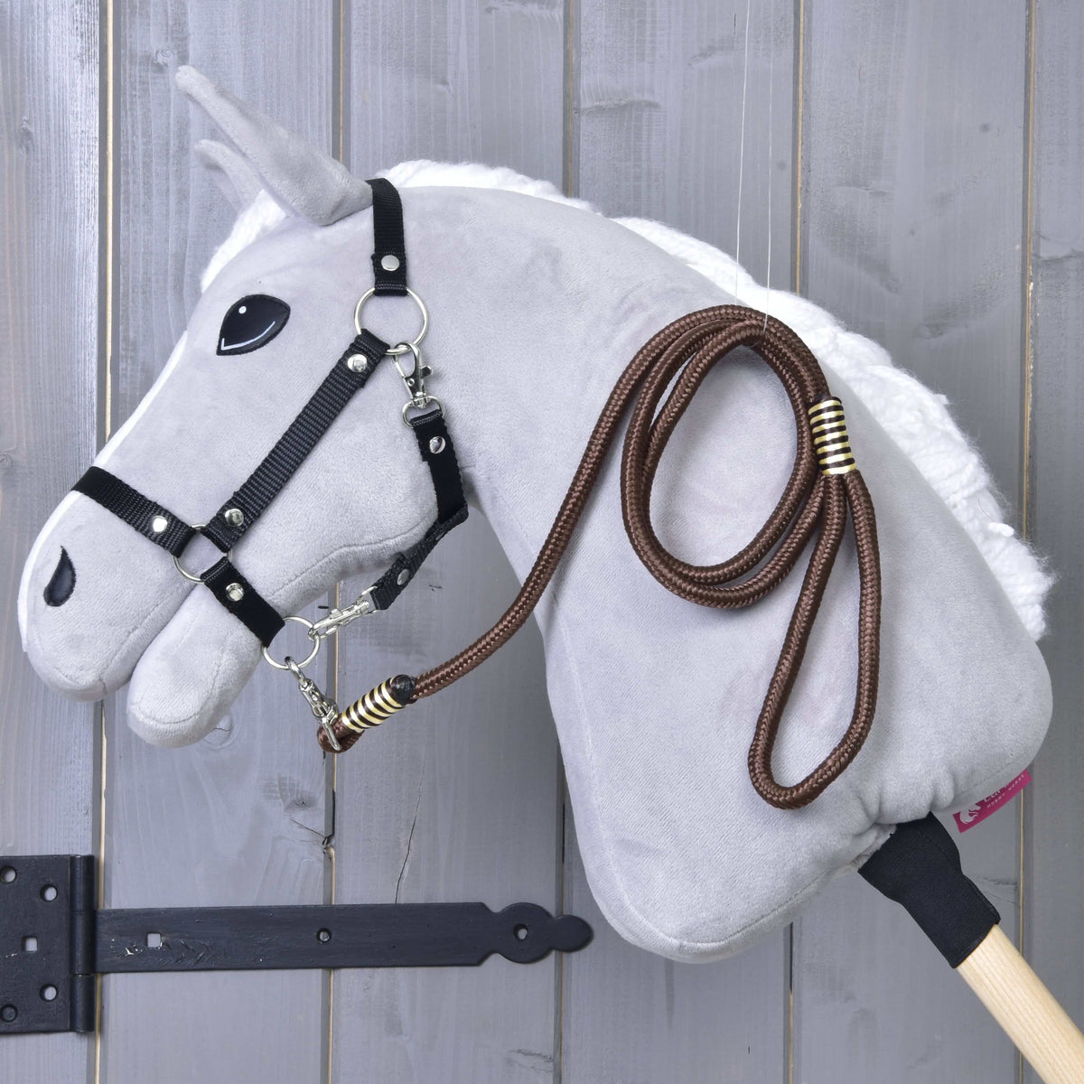 Lichtgrijze Hobby Horse met zwart halster en het bruine gestreepte halstertouw Vivaldi over de hals