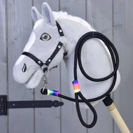 Grijze pluche Hobby Horse met zwart halster, het zwarte halstertouw met regenboogwikkels onder de kin vastgeklikt en ernaast opgerold
