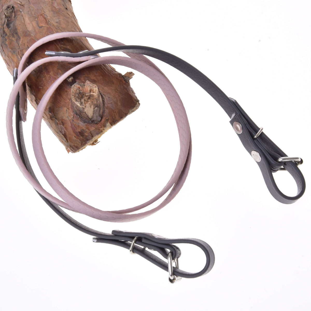 Teugels gerubberd Dark Grey/Pink van LarDen voor Hobby Horse, lichtroze midden en donkergrijze uiteinden met gespen, over een tak