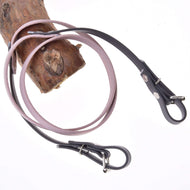 Teugels gerubberd Dark Grey/Pink van LarDen voor Hobby Horse, lichtroze midden en donkergrijze uiteinden met gespen, over een tak