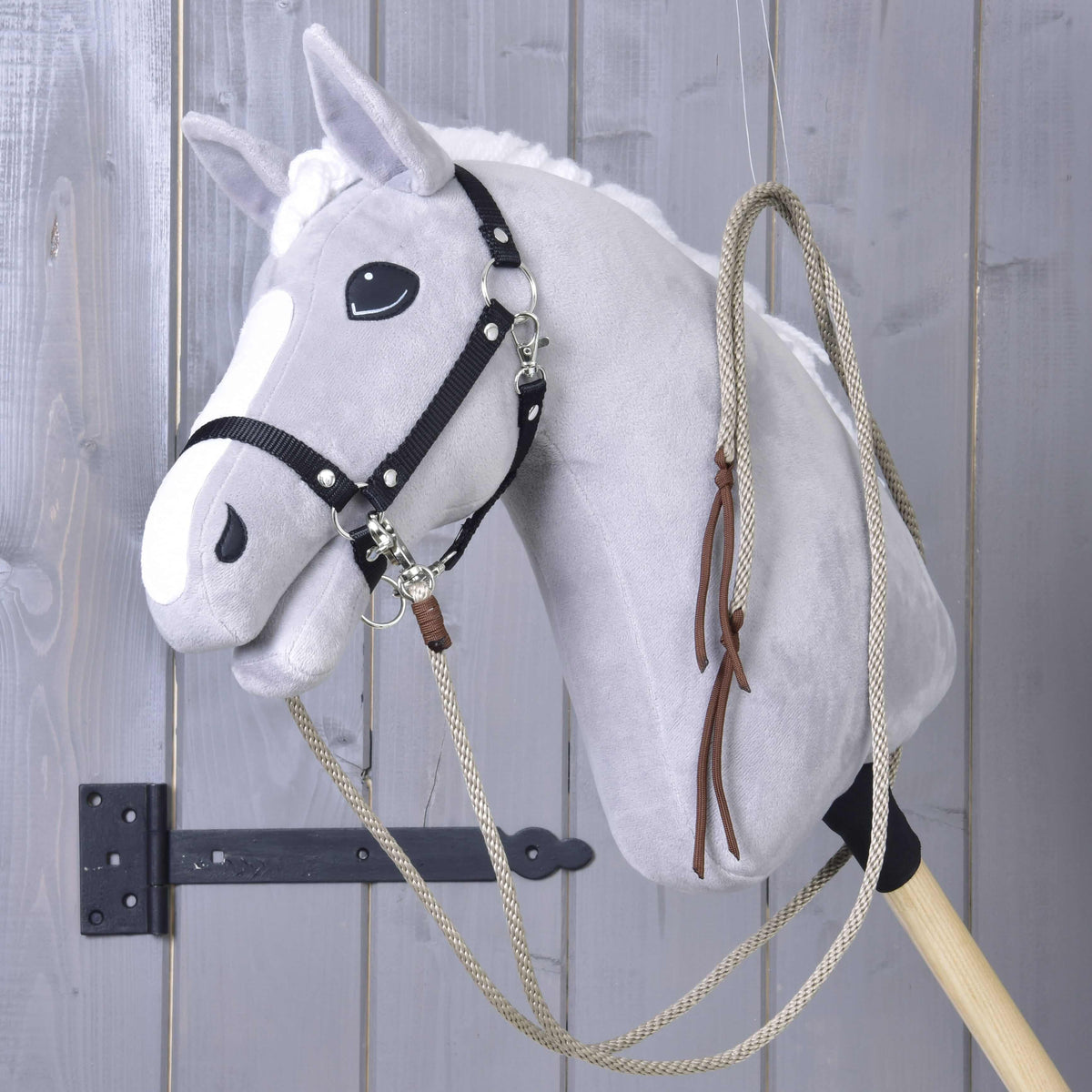 Rênes western beiges passées sur l’encolure d’un Hobby Horse gris, les extrémités en cuir marron pendant sur le côté