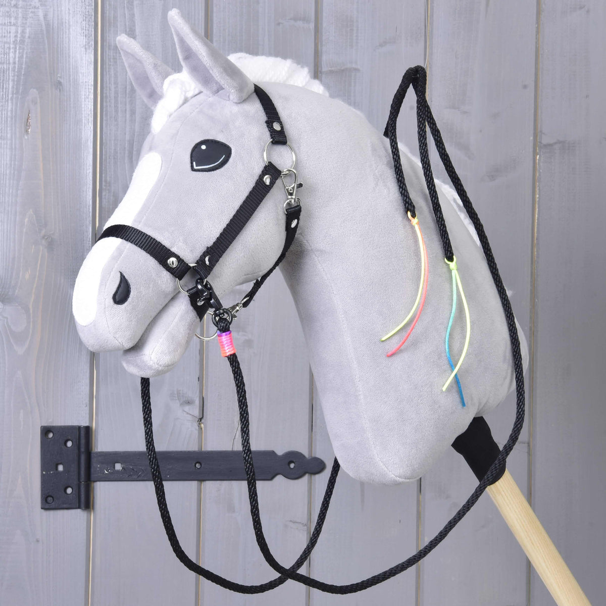 Grijze Hobby Horse met zwart halster en de zwarte westernteugels, neonkoordjes hangen langs de hals