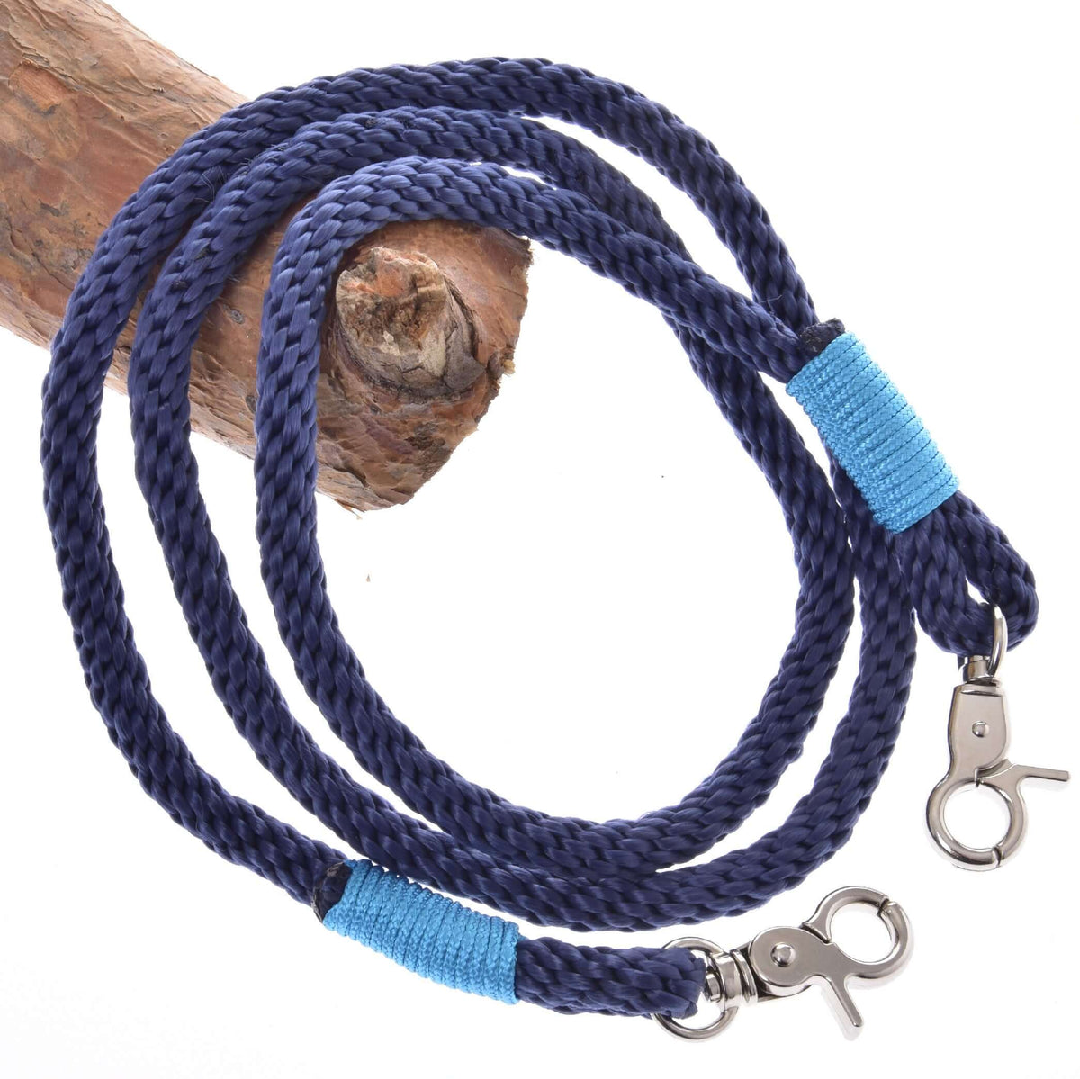 Marineblauwe teugels van gevlochten touw voor Hobby Horse met lichtblauwe omwikkeling en twee zilverkleurige musketonhaken over een tak