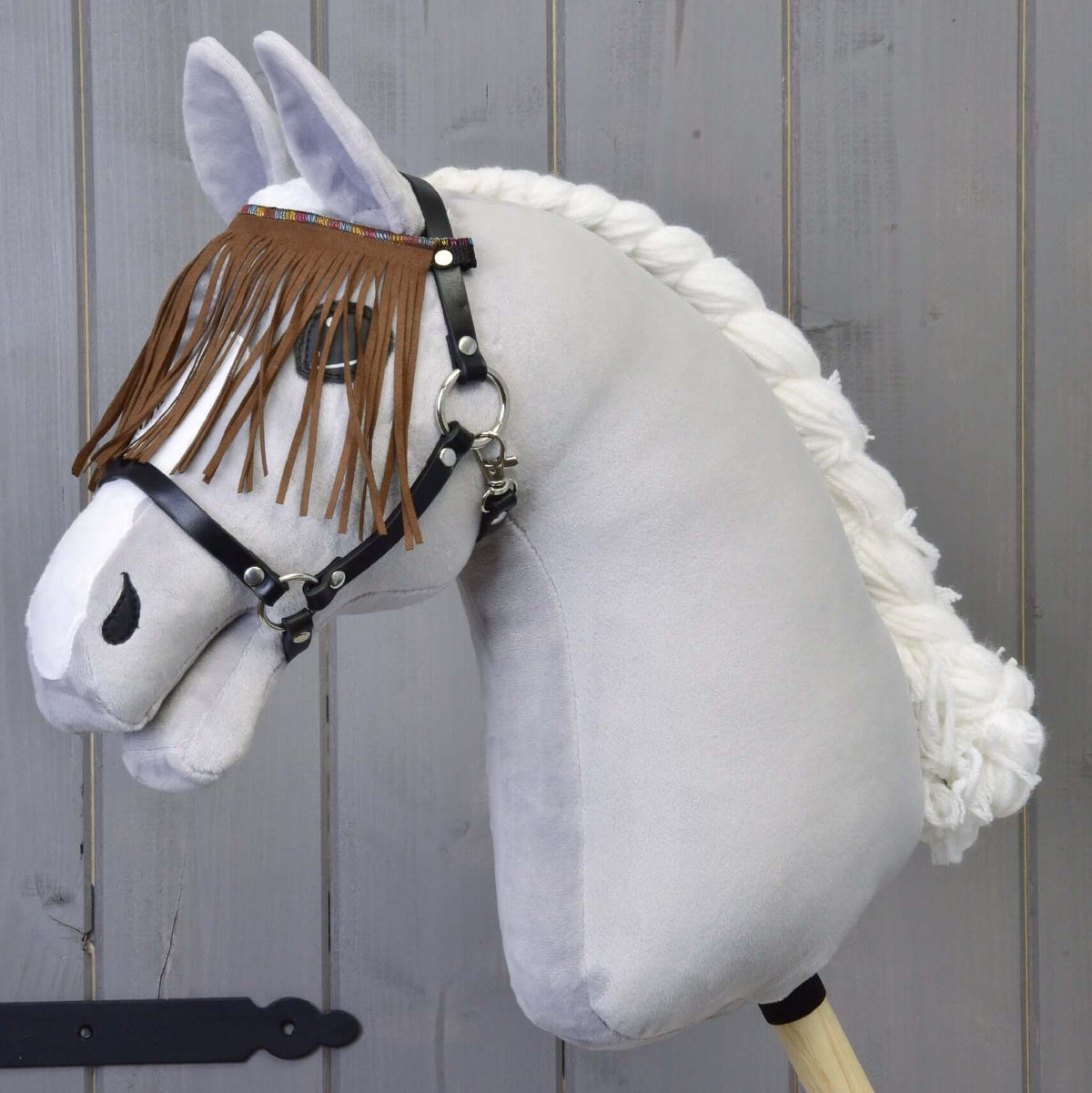 Halster zwart met bruine franjes van LarDen op een grijze pluche Hobby Horse, de franjes in suèdelook hangen over de ogen