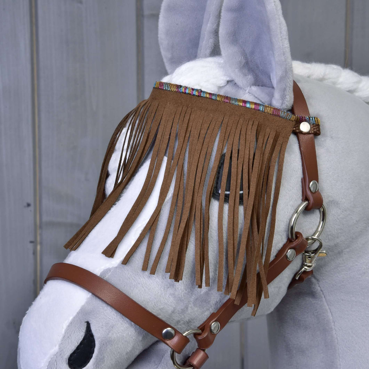 Close-up van de bruine franjeshoofdband met kleurrijke geweven rand aan de bruine halster voor Hobby Horse