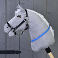 Een grijze pluche Hobby Horse met witte manen en zwarte halster draagt de felblauwe cordéo om de hals