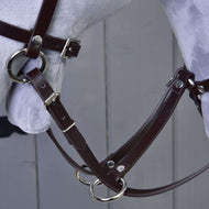Gros plan sur la martingale en similicuir marron foncé avec anneaux argentés et les rênes, sur un Hobby Horse gris