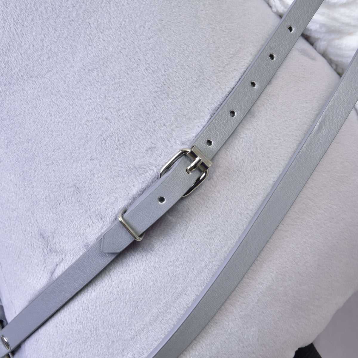 Close-up of a grey leatherette strap with a silver buckle across the grey plush neck of a Hobby Horse