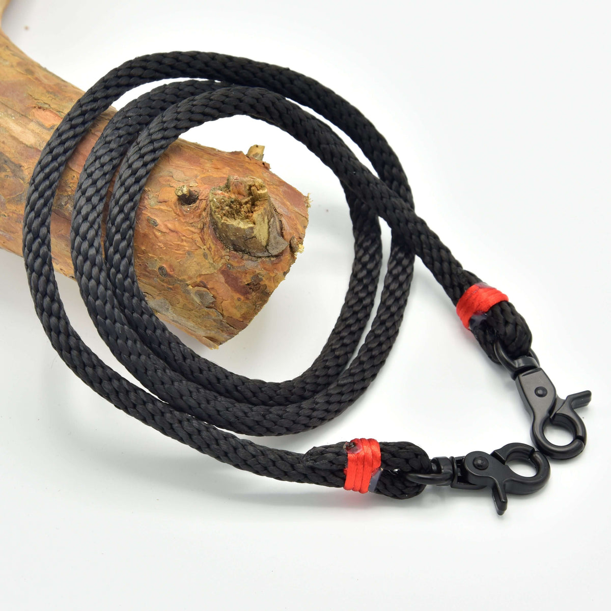 Teugels Spark voor Hobby Horse van LarDen van zwart gevlochten touw met rode omwikkeling en zwarte musketonhaken op een tak
